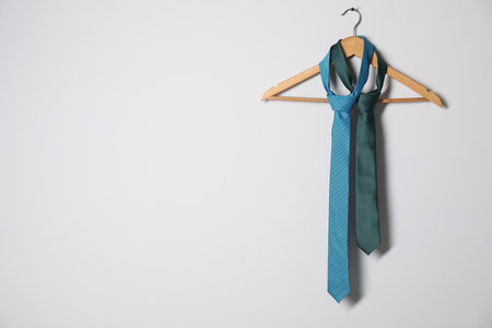 Hanger with different stylish neckties on light wall. Space for textの写真素材