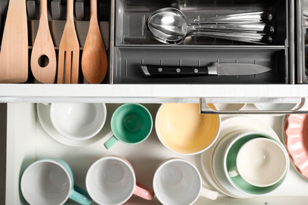 Ceramic dishware, utensils and cutlery in drawers, top viewの写真素材