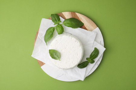 Fresh ricotta (cream cheese) and basil on green table, top viewの写真素材