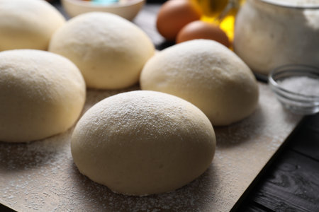 Raw dough balls on black wooden table, closeupの写真素材