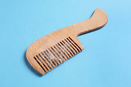 Wooden comb with lost hair on light blue backgroundの写真素材