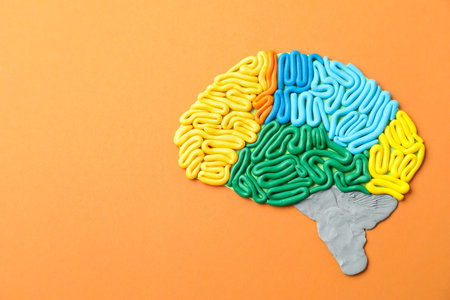 Amnesia problem. Brain with sections made of plasticine on orange background, top view. Space for...