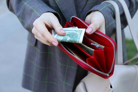 Woman holding purse with banknotes outdoors, closeupの写真素材