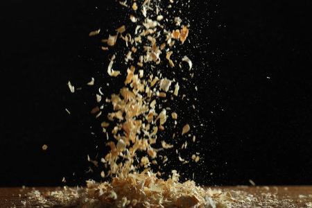Dry natural sawdust falling on table against black backgroundの写真素材