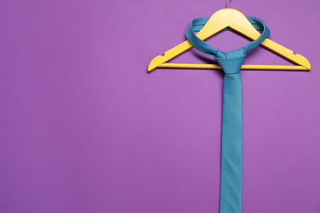 Hanger with necktie on purple background. Space for textの写真素材