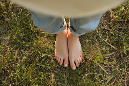 Woman standing barefoot on green grass outdoors, top viewの写真素材