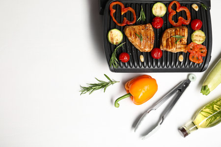 Flat lay composition with electric grill and different products on white tableの写真素材