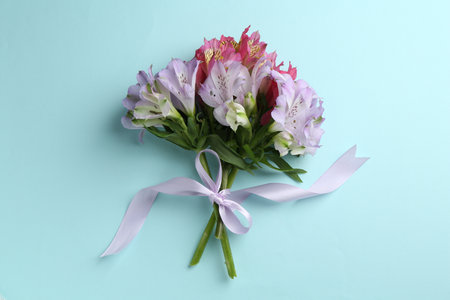 Bouquet of alstroemeria flowers and ribbon on light blue background, top viewの写真素材