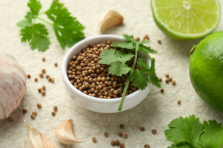 Fresh coriander leaves, dried seeds, garlic and limes on light textured table, closeupの写真素材