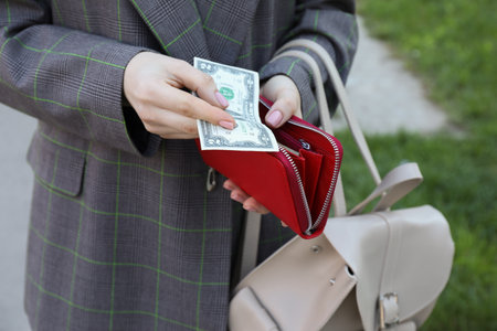 Woman holding purse with banknotes outdoors, closeupの写真素材