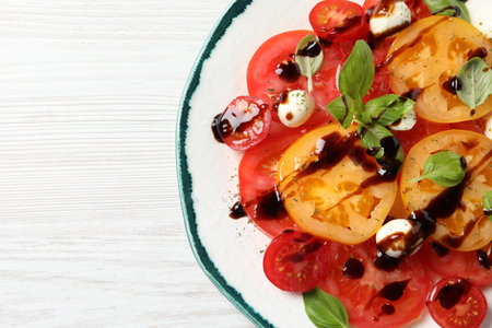 Tasty salad with balsamic vinegar and mozzarella on white wooden table, top view. Space for textの写真素材