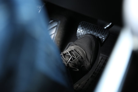 Man pushing on pedal of car brake, closeup