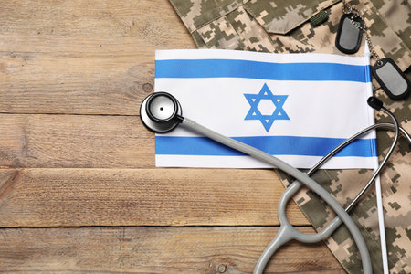 Stethoscope, flag of Israel, tags and military uniform on wooden table, flat lay. Space for textの写真素材