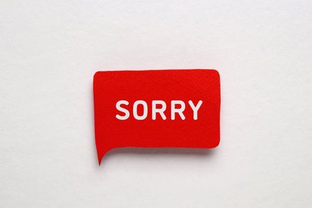 Red paper speech balloon with the word Sorry on light backgroundの写真素材