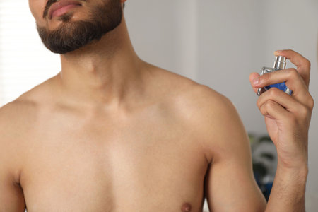 Young man spraying luxury perfume indoors, closeupの写真素材