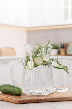 Refreshing cucumber water with rosemary and vegetable on table in kitchenの写真素材