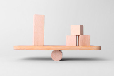 Equality concept. Seesaw scale with wooden blocks on light backgroundの写真素材