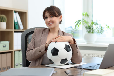 Smiling employee with soccer ball at table in officeの写真素材