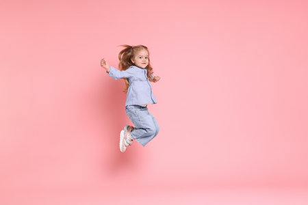 Cute little girl dancing on pink background, space for textの写真素材
