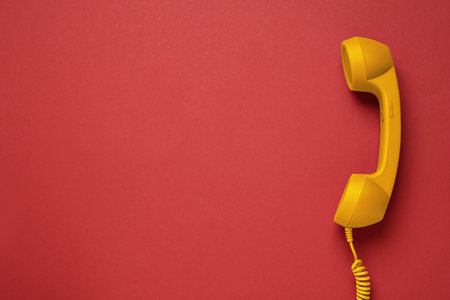 Orange telephone handset on red background, top view. Space for textの写真素材