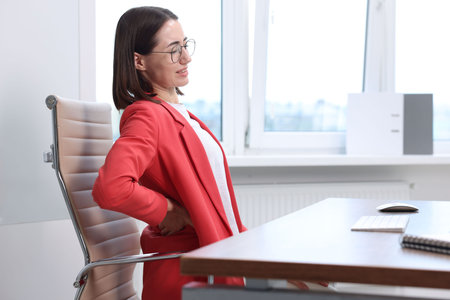 Woman suffering from back pain in office. Symptom of poor posture