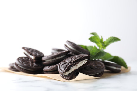 Tasty sandwich cookies and mint on white marble tableの写真素材
