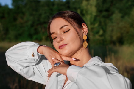 Beautiful woman in white shirt posing outdoorsの写真素材