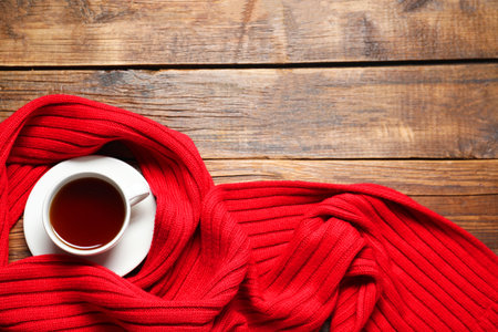 Red knitted scarf and tea on wooden table, top view. Space for textの写真素材
