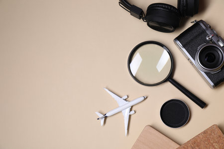 Travel blogger. Flat lay composition with vintage camera and magnifying glass on beige background, space for textの写真素材
