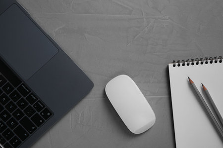 Wireless mouse, notebook, pencils and laptop on grey textured table, flat layの写真素材