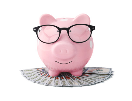 Pink piggy bank in glasses and money on white backgroundの写真素材