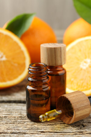 Essential oils in bottles, dropper and oranges on wooden tableの写真素材