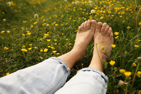 Woman sitting barefoot on green grass outdoors, closeup