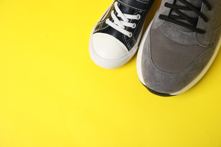 Big and small shoes on yellow background, above view. Space for textの写真素材