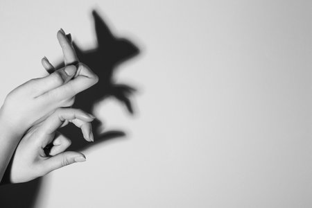 Shadow puppet. Woman making hand gesture like rabbit on light background, closeup with space for text. Black and white effectの写真素材