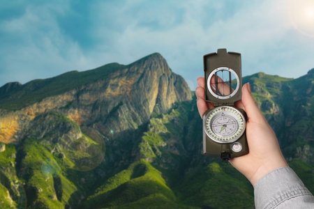 Woman using compass in mountains, closeup. Navigational instrumentの写真素材