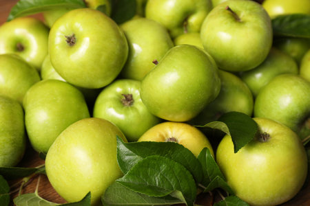 Fresh ripe green apples with leaves on wooden table, closeupの写真素材