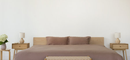 Stylish bedroom interior with large bed, flowers, bedside tables and lamps