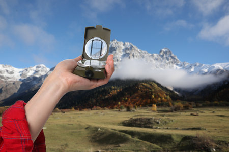 Woman using compass in mountains, closeup. Navigational instrumentの写真素材