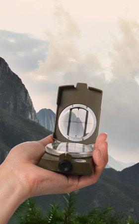 Woman using compass in mountains, closeup. Navigational instrument