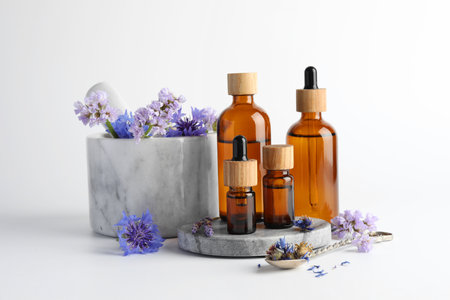 Aromatherapy. Different essential oils, flowers, mortar and pestle on white backgroundの写真素材