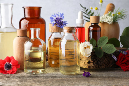 Aromatherapy. Different essential oils, flowers and green leaves on wooden tableの写真素材
