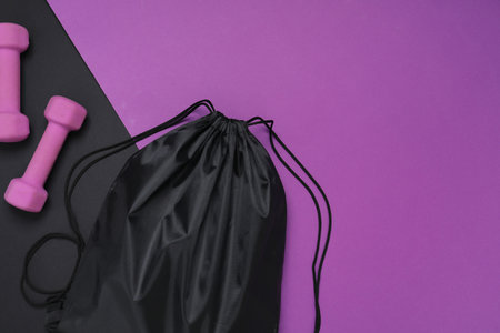 Black drawstring bag and dumbbells on color background, flat lay. Space for textの写真素材