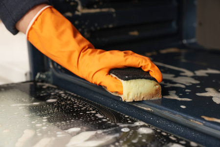 Woman cleaning oven with sponge in kitchen, closeupの写真素材