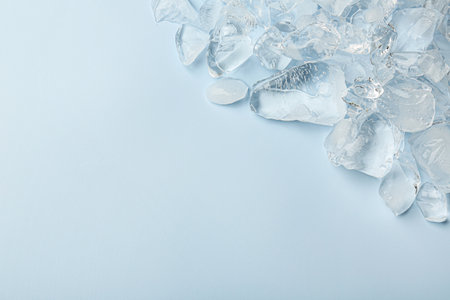 Pieces of crushed ice on light blue background, top view. Space for text
