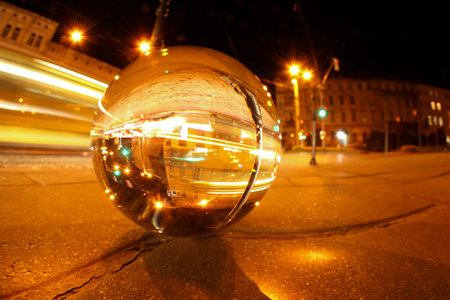 Beautiful city street, overturned reflection. Crystal ball on asphalt road at night. Space for text