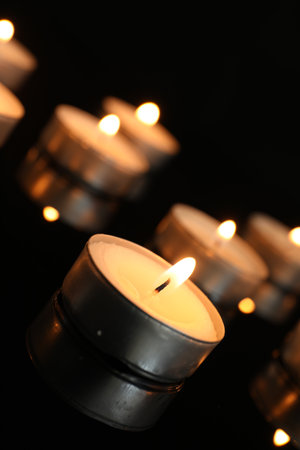 Many burning tealight candles on black background, closeupの写真素材