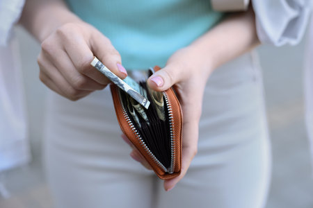 Woman holding purse with banknotes outdoors, closeupの写真素材