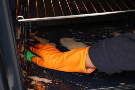 Woman cleaning oven with sponge, closeup viewの写真素材