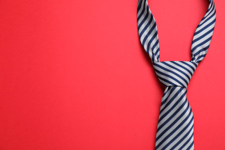 Striped necktie on red background, top view. Space for textの写真素材